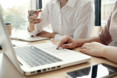 Midsection of woman using laptop on table