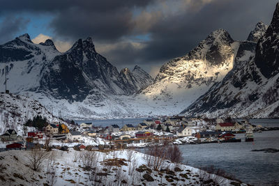 Scenic view of snowcapped townscape and mountains against sky during winter