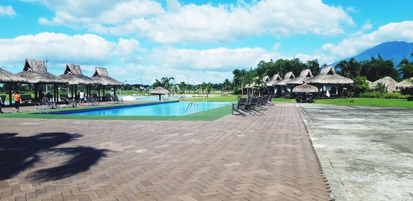 Panoramic view of swimming pool by building against sky