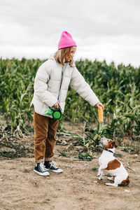 Full length of woman holding leash of dog at farm