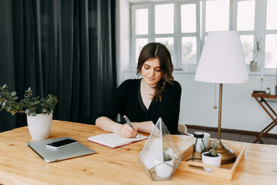 Business girl freelancer in casual clothes works using wireless technology in the home office