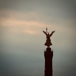 Low angle view of angel statue against cloudy sky