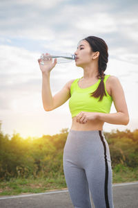 Woman drinking water while standing on road