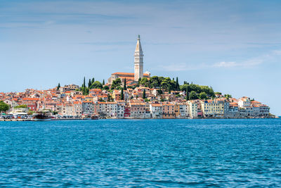 View of buildings by sea against sky in city