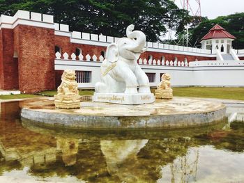 Statue by fountain against trees