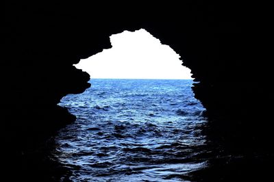 Silhouette of rock formation in sea