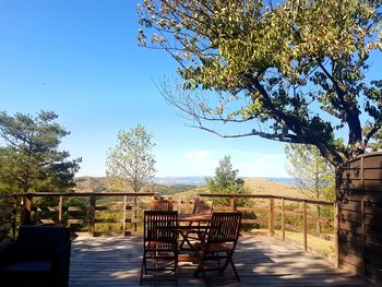 Empty chairs and table by sea against clear sky