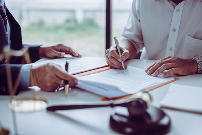 Midsection of man holding paper at table