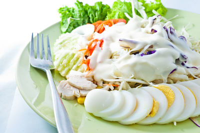 High angle view of salad with boiled egg and meat in plate on table