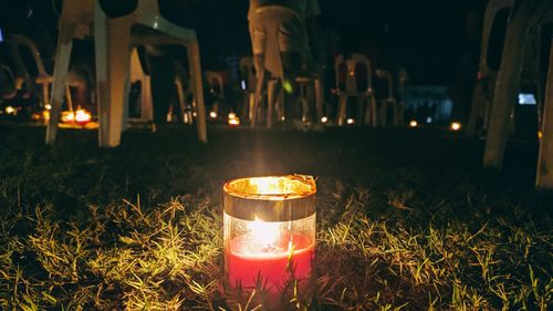 Illuminated tea light candles on field at night