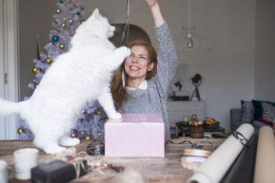 Woman playing with cat while packing present