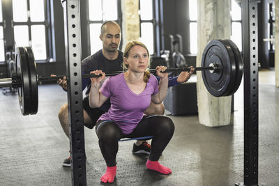 Man assisting woman exercising in gym