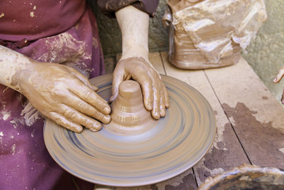Midsection of woman working on pottery wheel