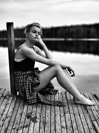 Young woman looking away while sitting on pier