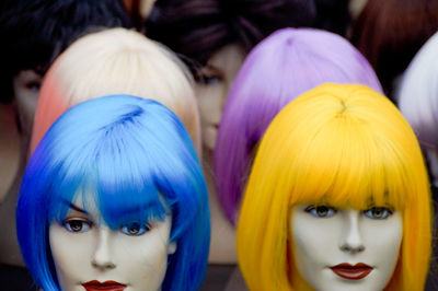 Close-up of colorful wigs on mannequins