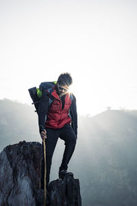 Young traveler in red snow jacket and a backpack standing on blue isolated background..