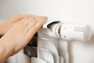 Woman hands on white heating radiator, close up view. it is cold, person warms up. central heating