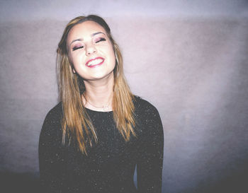 Smiling young woman against wall