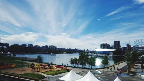 View of city at waterfront against cloudy sky