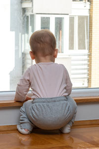 Side view of boy sitting on floor at home