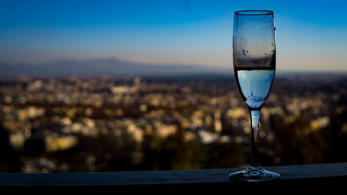 Close-up of drink on railing against sky