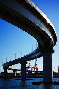 Low angle view of bridge over river against blue sky