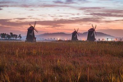 Traditional windmill on field against sky during sunset