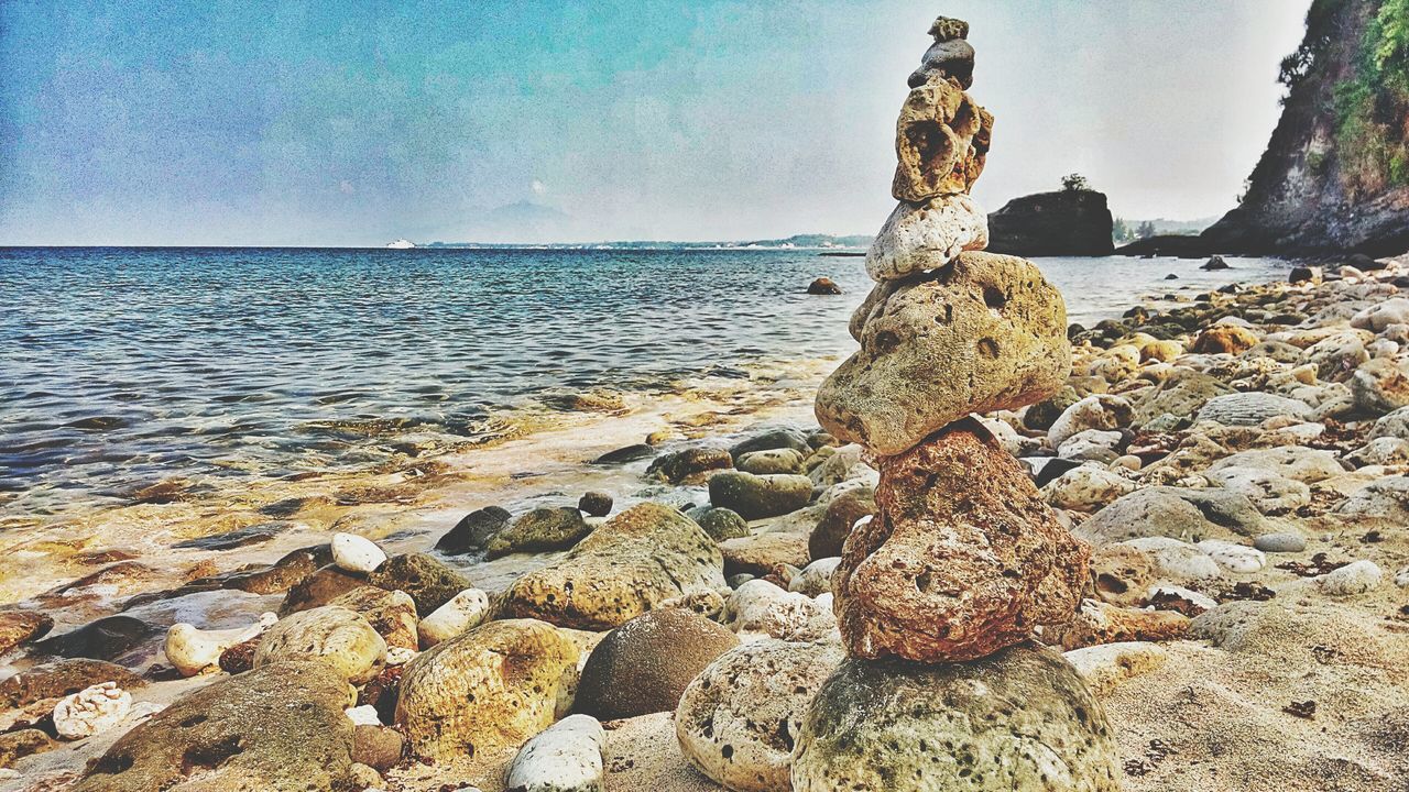 sea, water, beach, horizon over water, tranquility, tranquil scene, nature, rock - object, beauty in nature, shore, scenics, sky, blue, clear sky, sunlight, rock formation, idyllic, stone - object, day, rock