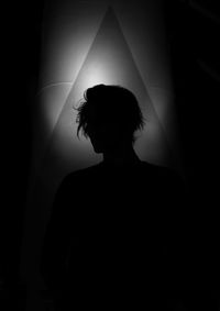 Rear view of silhouette woman standing against wall at home