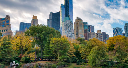 Trees and buildings in city against sky