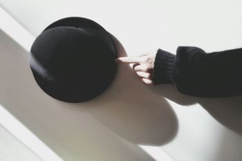 Cropped hand touching black hat