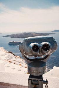 Close-up of coin-operated binoculars on beach against sky