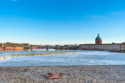 View of sea and buildings against blue sky