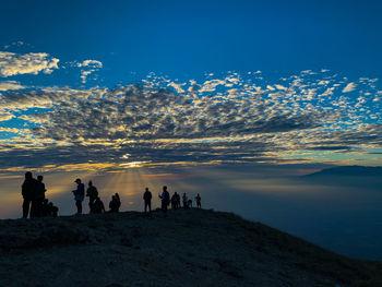 Silhouette people by mountain against sky during sunset