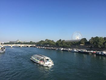 Boats in sea against clear blue sky