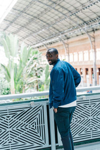 Portrait of man standing against railing