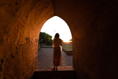 Rear view of woman standing at archway