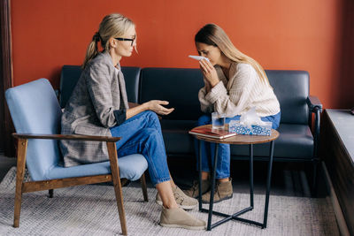 Professional psychologist listens to the problems of a crying modern woman on a visit in the office.