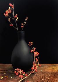 Close-up of red rose in vase against black background