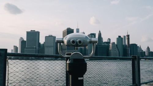 Close-up of coin-operated binoculars with city in background