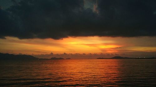 Scenic view of sea against cloudy sky at sunset