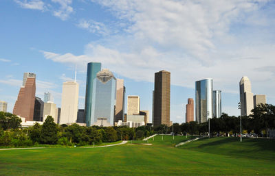 View of skyscrapers in park against cloudy sky