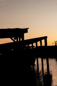 Silhouette bridge over lake against sky during sunset