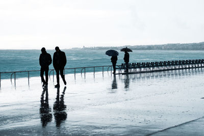 Silhouette people standing on beach against sky