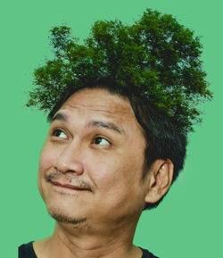 Digital composite image of trees growing of man head against green background