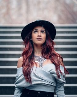 Portrait of beautiful young woman standing against wall