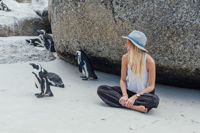 Woman with penguins sitting at beach