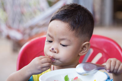 Close-up of cute boy with nose injury eating food while sitting at home