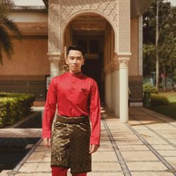 Portrait of smiling man in traditional clothing standing against building