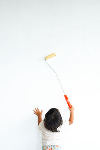 Rear view of woman holding tape measure against white background